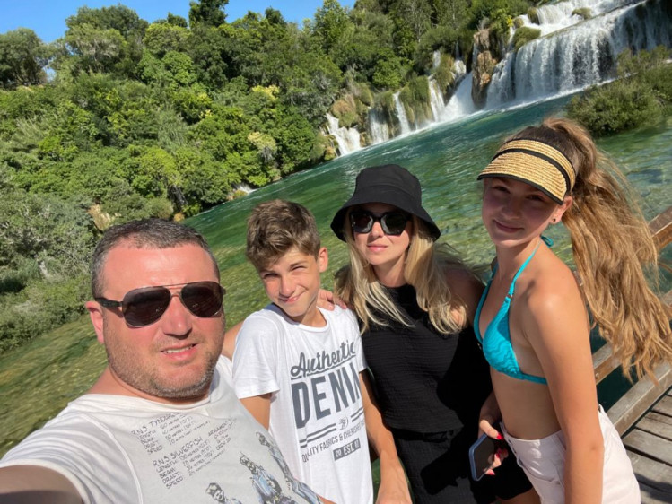 Сергей Гамалий с семьей позирует на фоне водопада